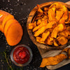 arrangement-suesskartoffelchips-mit-suesskartoffel-und-ketchup-auf-schneidebrett