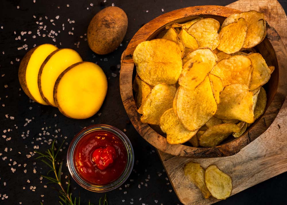 arrangement-kartoffelchips-mit-kartoffel-und-ketchup-auf-schneidebrett