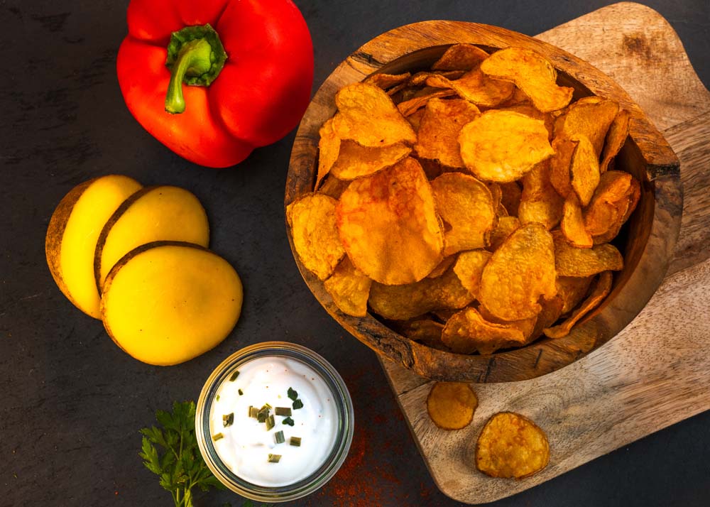 arrangement-kartoffelchips-mit-kartoffel-und-paprika-auf-schneidebrett